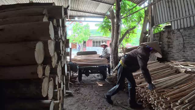 Workers Loading Cart With Poles