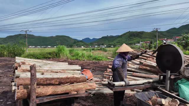 Worker Trimming Wooden Poles