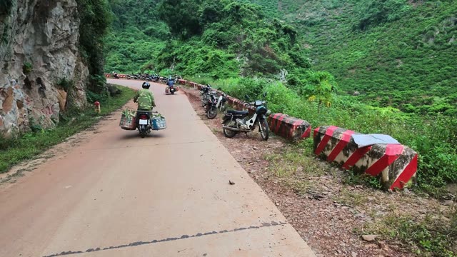 Man Walking Loaded Motorbike Along Road