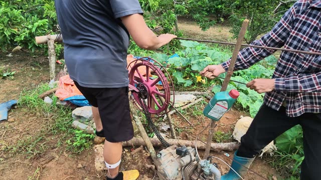 Two Farmers Repairing Pump Chain