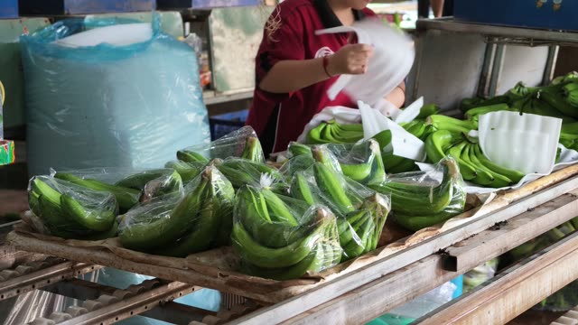 Worker Wrapping Banana Hands In Plastic