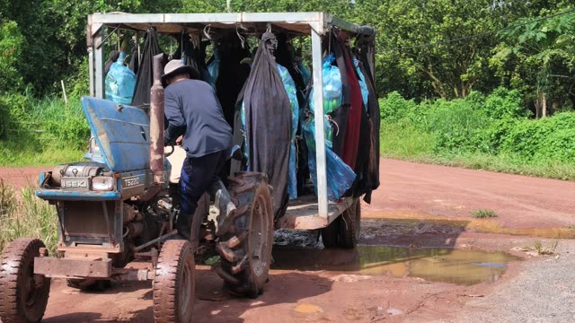 Farmer Driving Tractor With Bag Trailer