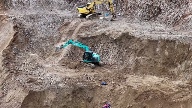 Two Excavators Digging Rocky Pit