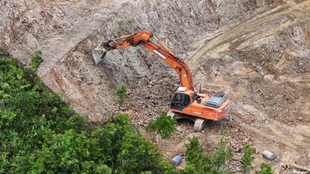 Excavator On Mountain Ridge Above Town