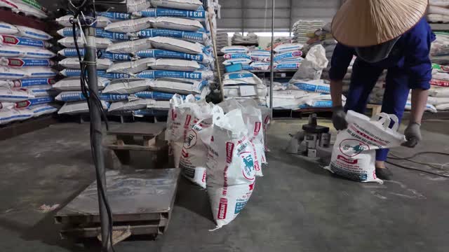 Worker Bagging Feed In Warehouse