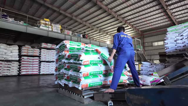 Worker Stacking Feed Sacks Pallet