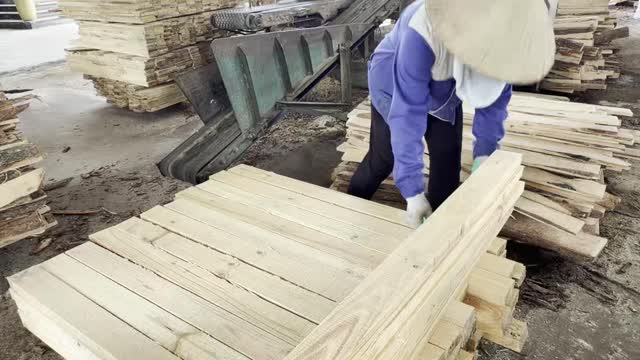 Worker Stacking Sawn Planks