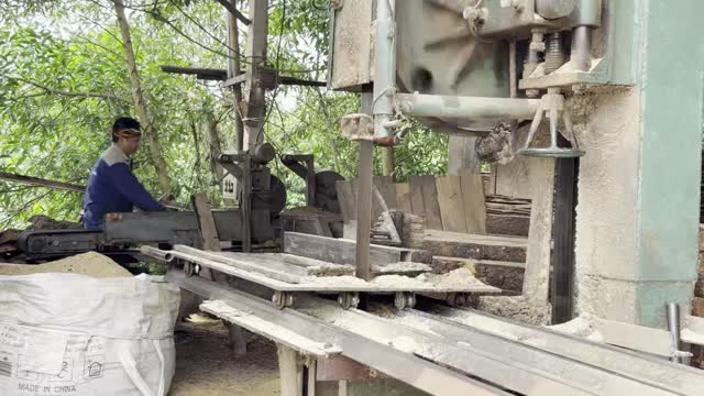 Worker Sawing Log Into Planks